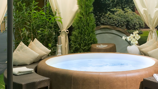 A backyard hot tub with beautiful drapes, landscaping, and design.