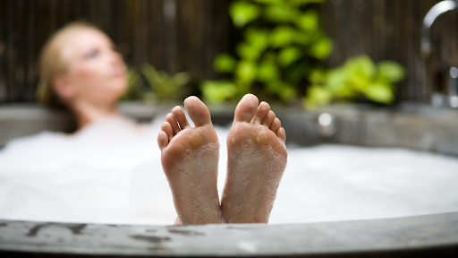 A woman reclines in a hot tub with her feet raised