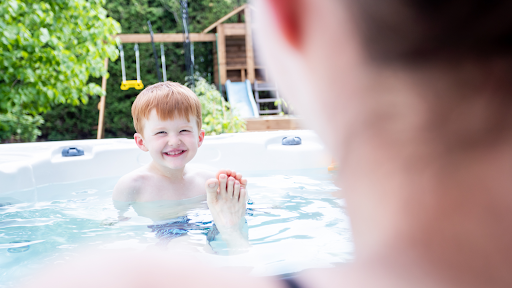 A happy boy smiles at his mother in a hot tub.