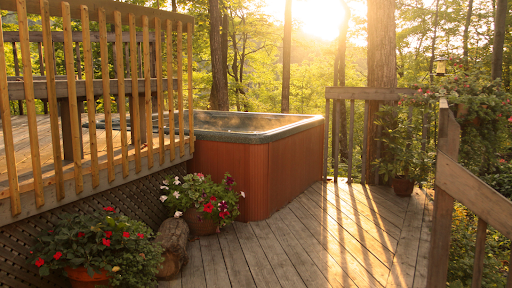 A multi-level deck with flowers and a hot tub with a beautiful view of the forest