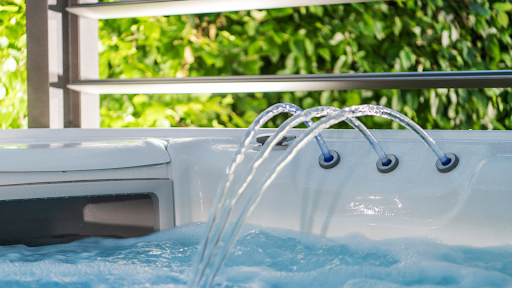 A close-up view of a hot tub with water jets on, surrounded by lush greenery.