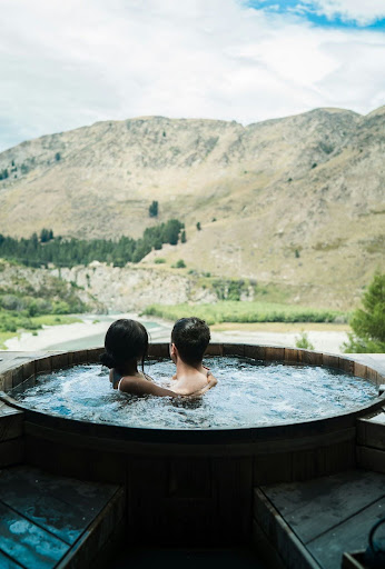 two people holding each other in a hot tub, overlooking a river
